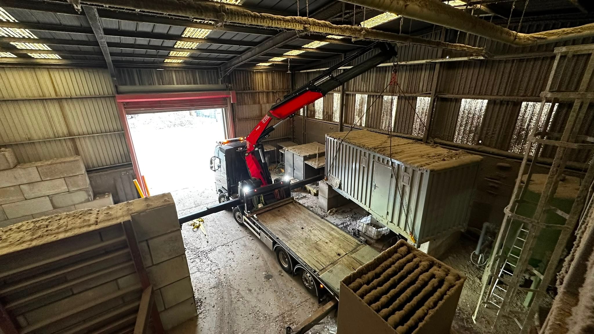 Fassi crane lifting a modular unit inside a warehouse
